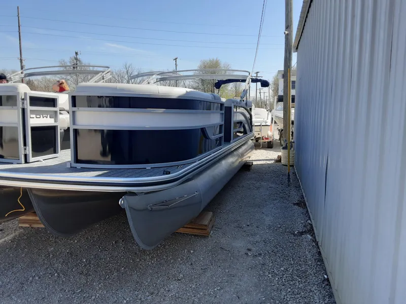 The Image of 2023 Lowe SS 230 pontoon boat parked on gravel near a metal building. - 0