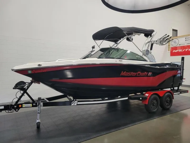 Slide: The Image of 2018 MasterCraft XT22 boat with trailer, black and red design, indoor display. - 15
