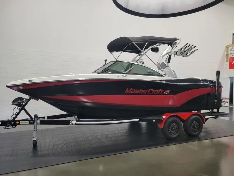 Slide: The Image of 2018 MasterCraft XT22 boat with red and black design on a trailer. - 6