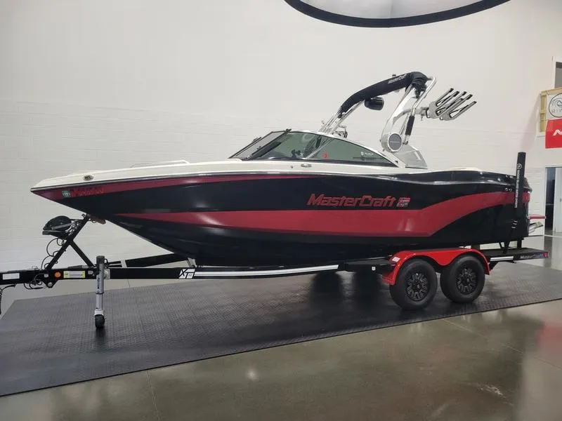 Slide: The Image of 2018 MasterCraft XT22 boat on trailer, black and red design, indoor showroom. - 7
