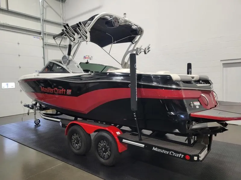 Slide: The Image of 2018 MasterCraft XT22 boat on trailer in garage, black and red design. - 8
