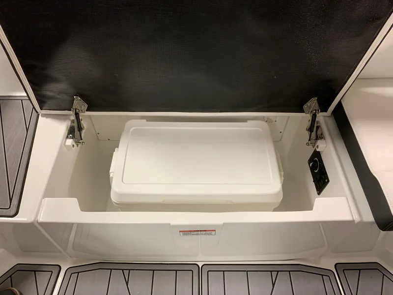 Slide: The Image of 2023 Monterey 218 Super Sport boat storage compartment with white cooler inside. - 13