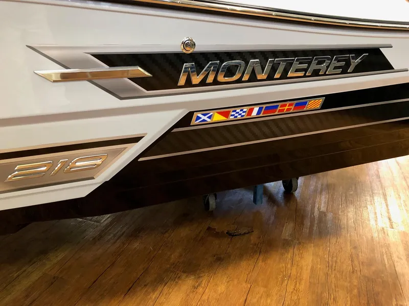 Slide: The Image of 2023 Monterey 218 Super Sport boat with nautical flags on wooden floor. - 2
