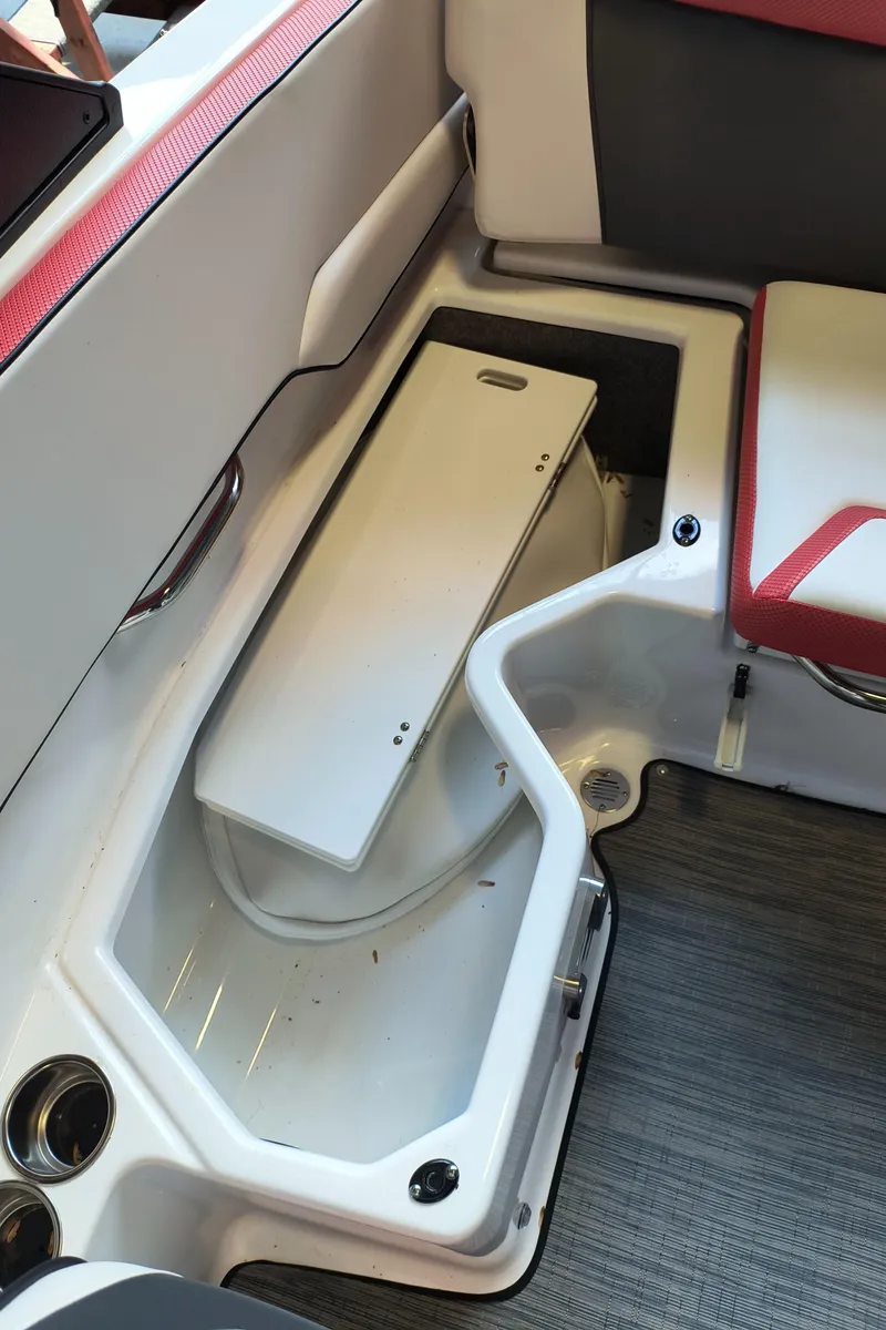 Slide: The Image of 2023 Scarab 195 ID boat interior storage compartment with red and white seating. - 26