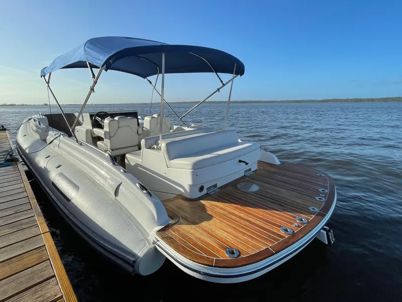 Slide: The Image of 2011 Novurania Chapman Transition 28 boat docked, featuring a blue canopy and wooden deck. - 1