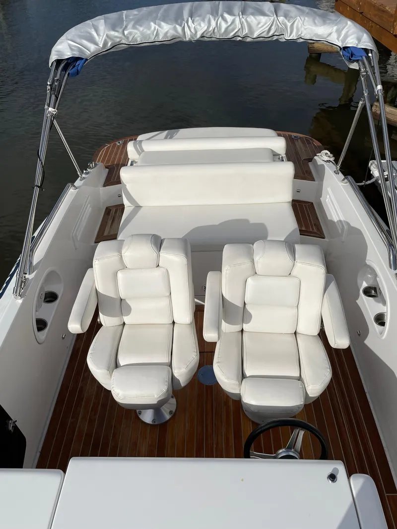 Slide: The Image of 2011 Novurania Chapman Transition 28 boat interior with white seating and wooden deck. - 12