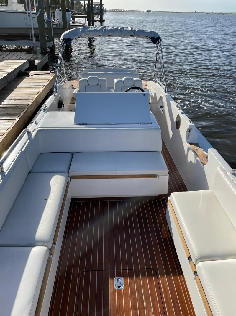 Slide: The Image of 2011 Novurania Chapman Transition 28 boat with white seating and wooden deck, docked by the water. - 9