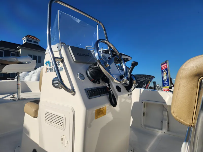 Slide: The Image of 2018 Key West 176 Center Console boat with steering wheel and controls under clear blue sky. - 11
