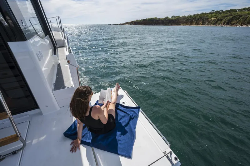Slide: The Image of Woman relaxing on Jeanneau NC 1295 FLY 2024 yacht, reading a book by the sea. - 10