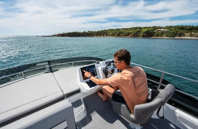 Slide: The Image of Man navigating Jeanneau NC 1295 Fly 2024 boat on open water. - 20