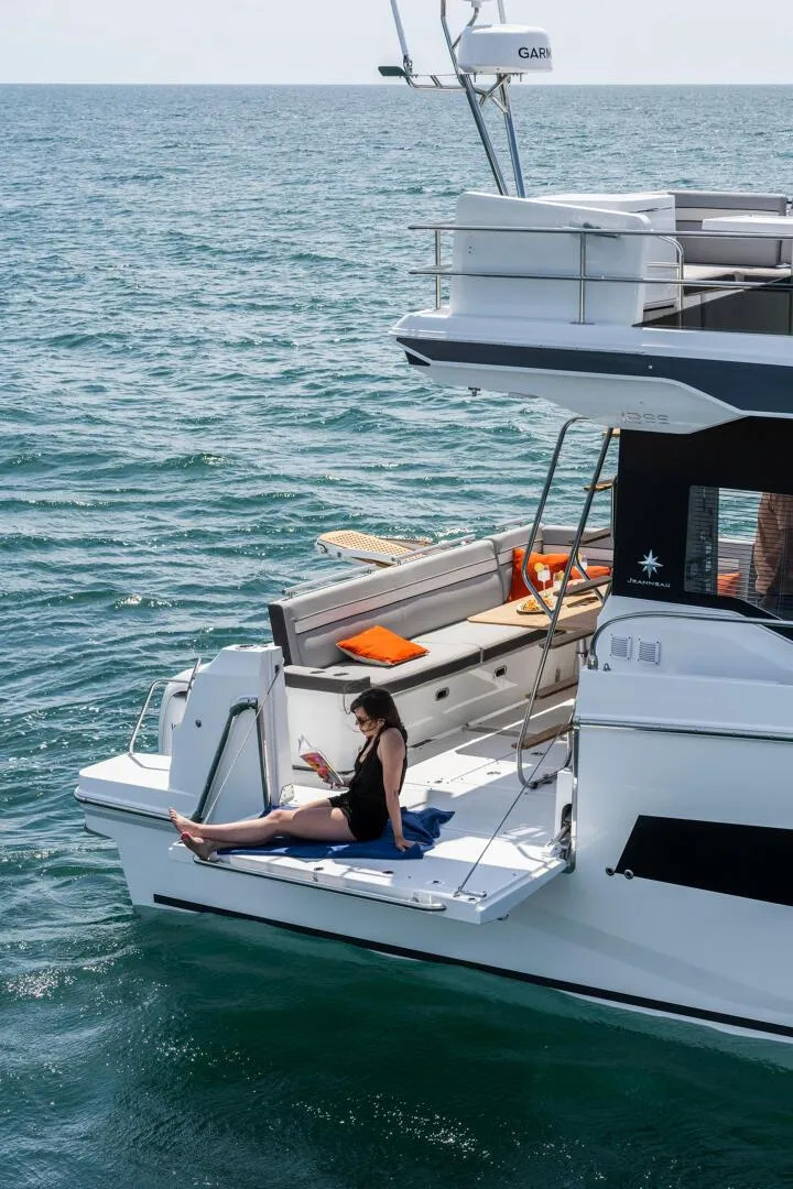 Slide: The Image of 2024 Jeanneau NC 1295 FLY yacht with a woman relaxing on the deck. - 9