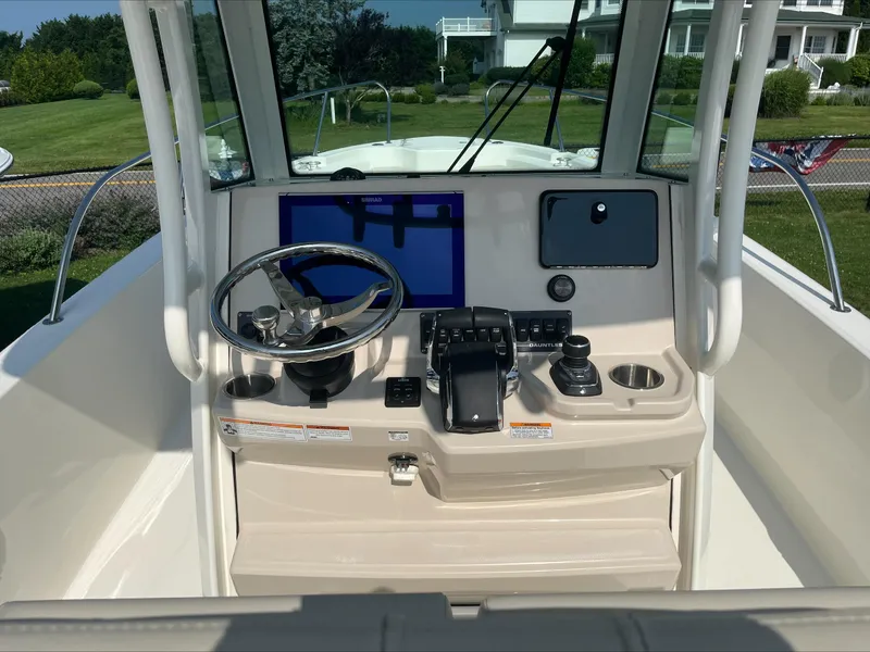 Slide: The Image of 2023 Boston Whaler 280 Dauntless helm with steering wheel, controls, and navigation display. - 14