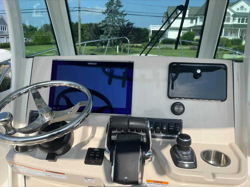 Slide: The Image of 2023 Boston Whaler 280 Dauntless helm with steering wheel, controls, and navigation screen. - 15