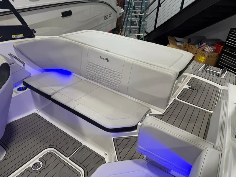 Slide: The Image of 2023 Sea Ray SPX 190 boat interior with blue LED lighting and cushioned seating. - 31