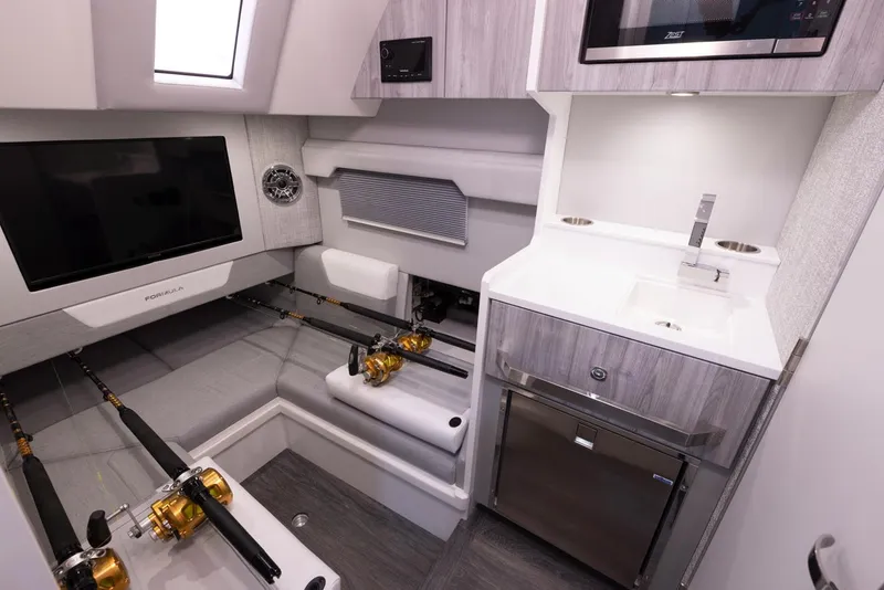 Slide: The Image of 2023 Formula 387 Center Console Fish cabin with fishing rods, TV, and kitchenette. - 24