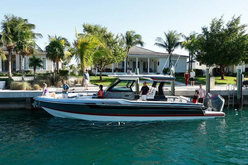 The Image of 2023 Formula 387 Center Console Sport boat docked near waterfront homes. - 0