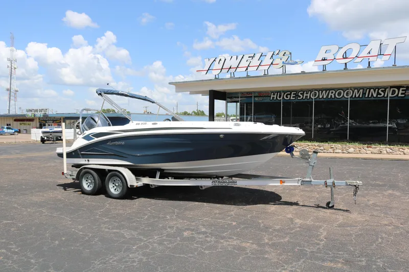 Slide: The Image of 2023 Hurricane SUN DECK 205 OB boat on a trailer outside a showroom. - 1