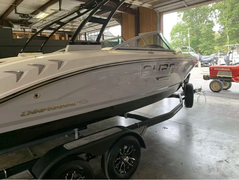 The Image of 2023 Chaparral 21 Surf boat in a garage, side view. - 0