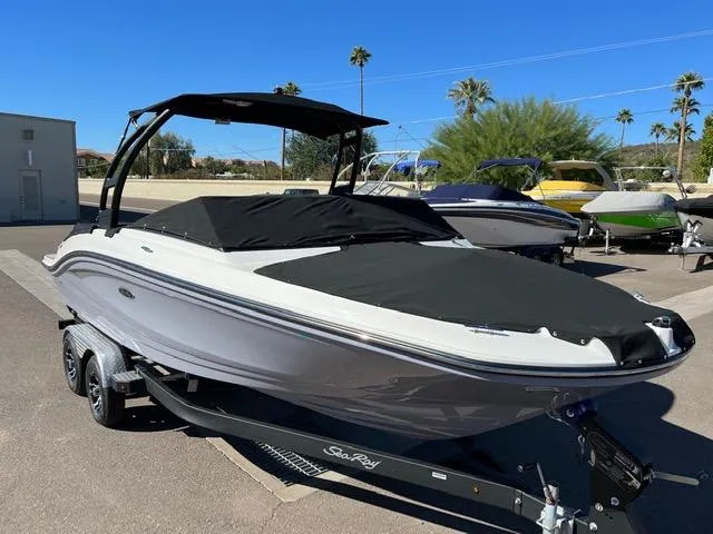 Slide: The Image of 2023 Sea Ray SPX 210 boat with black cover on trailer, parked outdoors. - 23