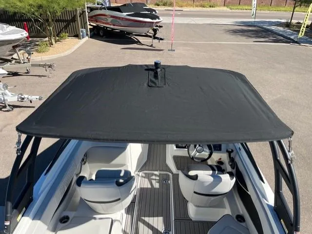 Slide: The Image of 2023 Sea Ray SPX 210 boat with black canopy and white interior, parked outdoors. - 24