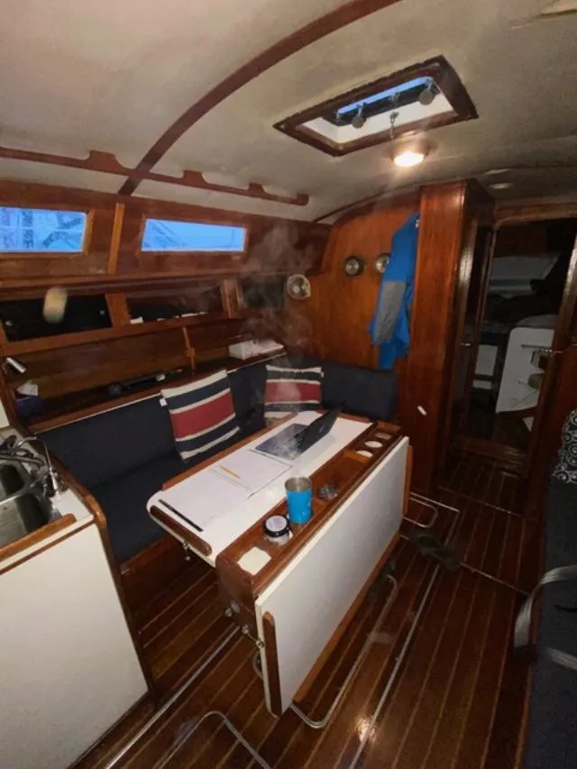 Slide: The Image of 1979 Columbia 10-7 sailboat interior with wooden finish, table, and seating area. - 2