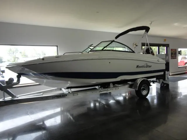 The Image of 2022 NauticStar 203DC Sport Deck boat on trailer in showroom. - 0
