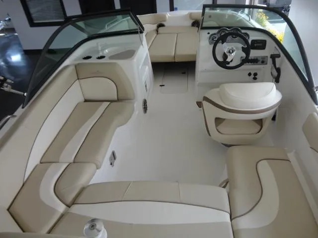 Slide: The Image of 2022 NauticStar 203DC Sport Deck boat interior with beige seating and steering console. - 2