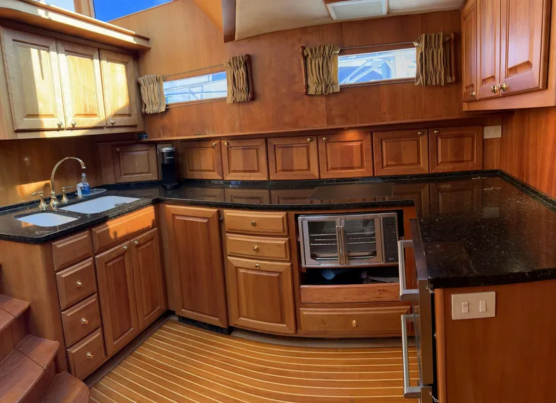 Slide: The Image of Luxurious 2004 Legacy Downeast yacht kitchen with wooden cabinetry and black countertops. - 18