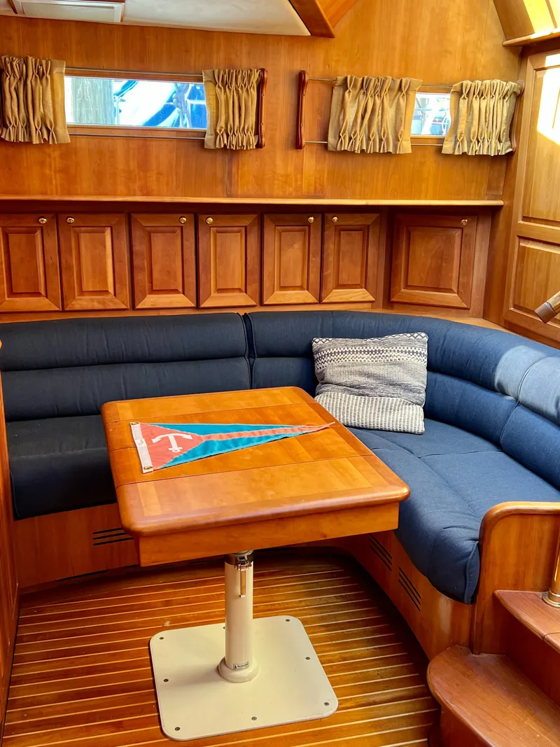 Slide: The Image of 2004 Legacy Downeast yacht interior with wooden paneling and blue cushioned seating. - 19