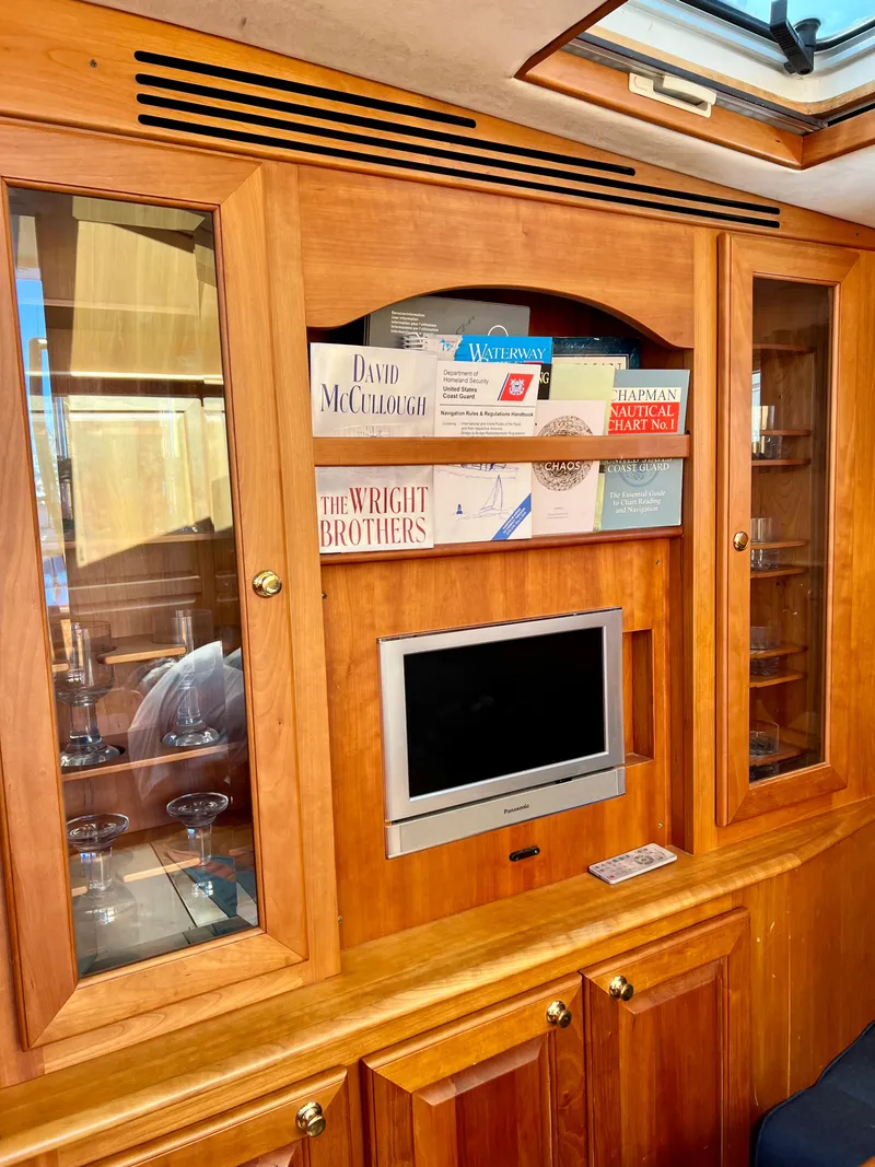Slide: The Image of Wooden interior of 2004 Legacy Downeast boat with TV, books, and glass cabinets. - 24
