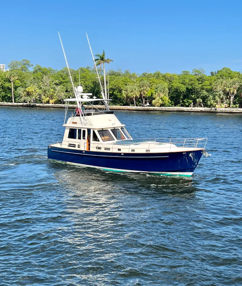 Slide: The Image of 2004 Legacy Downeast boat cruising on a sunny day, surrounded by lush greenery. - 3