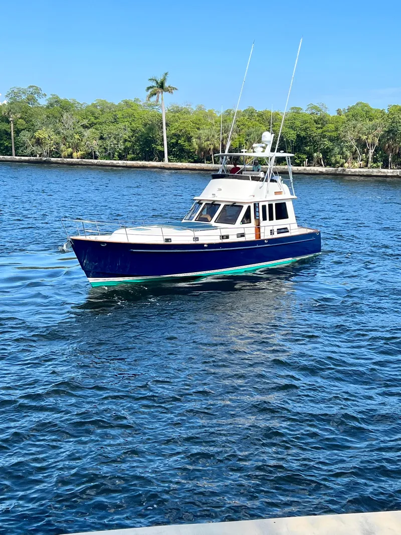 Slide: The Image of 2004 Legacy Downeast boat cruising on a sunny day in a scenic waterway. - 5