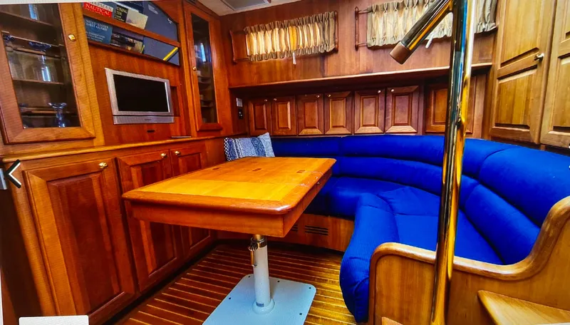 Slide: The Image of 2004 Legacy Downeast yacht interior with blue seating, wooden table, and cabinetry. - 9