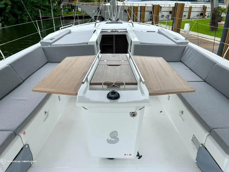 Slide: The Image of 2024 Beneteau Oceanis 51.1 yacht cockpit with wooden table and cushioned seating. - 2