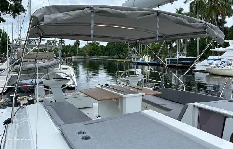 Slide: The Image of 2024 Beneteau Oceanis 51.1 yacht with spacious deck and canopy, docked by a serene waterfront. - 4