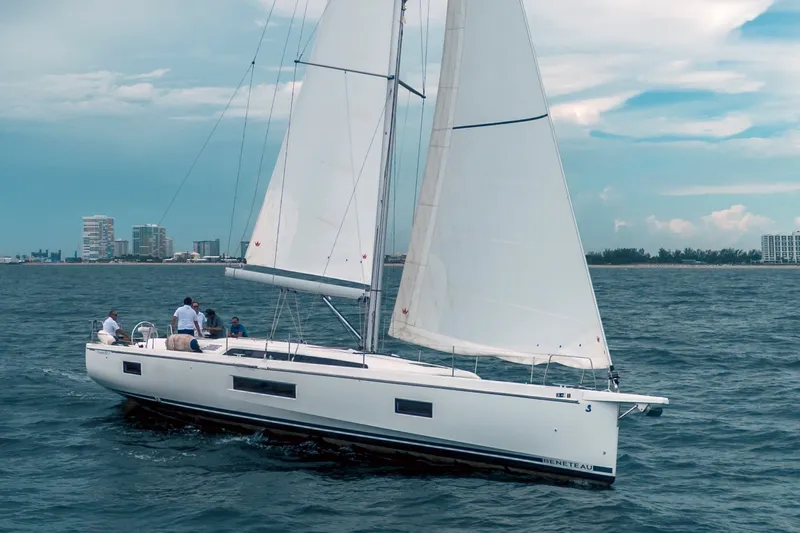 The Image of 2024 Beneteau Oceanis 51.1 sailboat on the water with several people on board. - 0