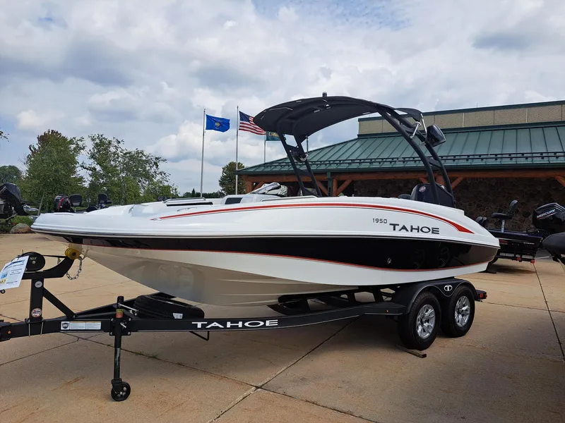 Slide: The Image of 2023 Tahoe 1950 boat on trailer, displayed outdoors with flags in the background. - 2