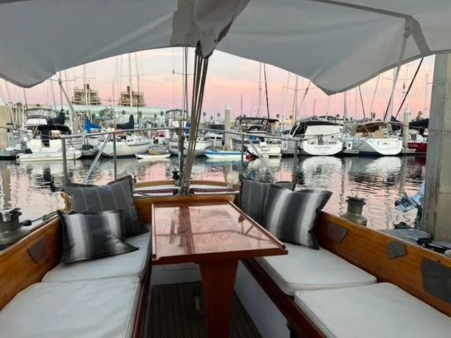 Slide: The Image of Cozy seating on a 1961 Lapworth 40 yacht at sunset in a marina. - 17