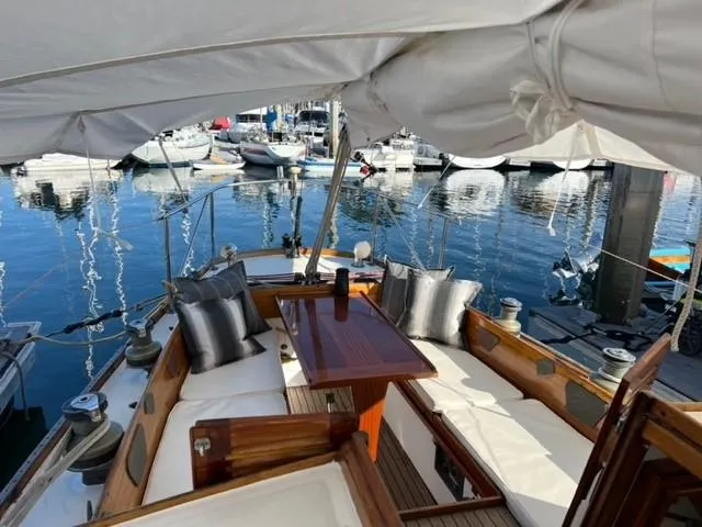 Slide: The Image of 1961 Lapworth 40 sailboat interior with cushioned seating and wooden table at marina. - 21