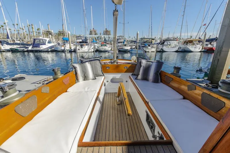 Slide: The Image of 1961 Lapworth 40 sailboat cockpit with white cushions, docked in a marina. - 30