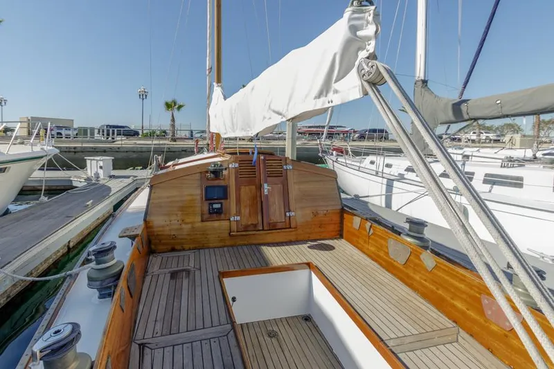 Slide: The Image of 1961 Lapworth 40 sailboat with wooden deck and white sails docked at marina. - 32