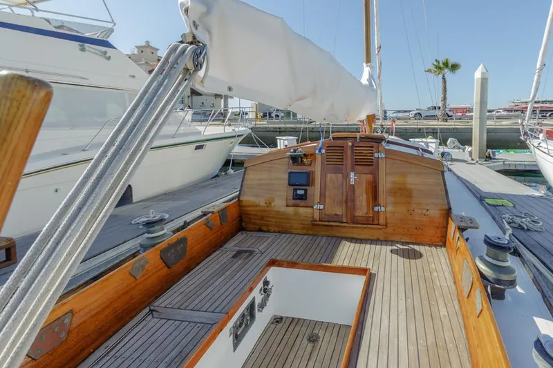 Slide: The Image of Sailboat deck of a 1961 Lapworth 40, featuring wooden details and docked in a marina. - 33
