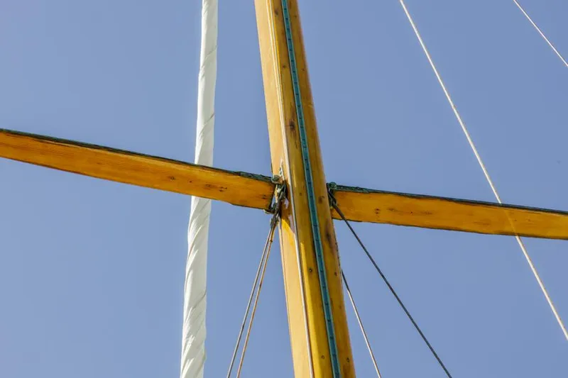 Slide: The Image of Wooden mast and rigging of a 1961 Lapworth 40 sailboat against a clear blue sky. - 40