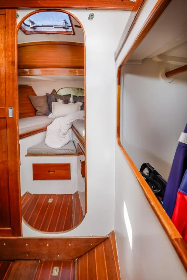 Slide: The Image of Cozy cabin interior of a 1961 Lapworth 40 sailboat with wooden accents and bedding. - 49