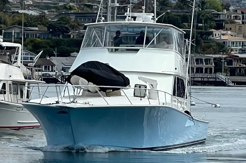 Slide: The Image of 2000 Viking 65 Convertible yacht cruising in a marina, featuring a sleek blue hull. - 0