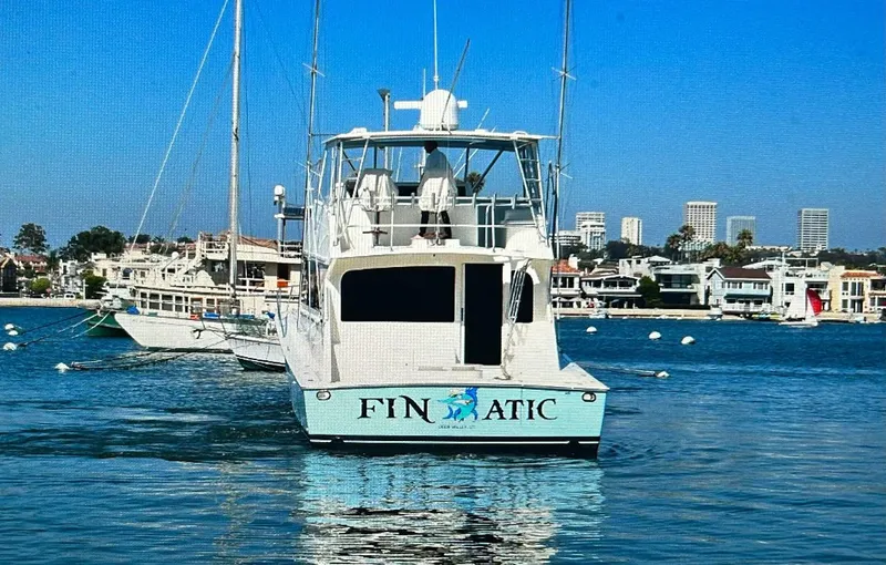 Slide: The Image of Viking 65 Convertible yacht "FINATIC" on water, cityscape background, clear blue sky. - 2