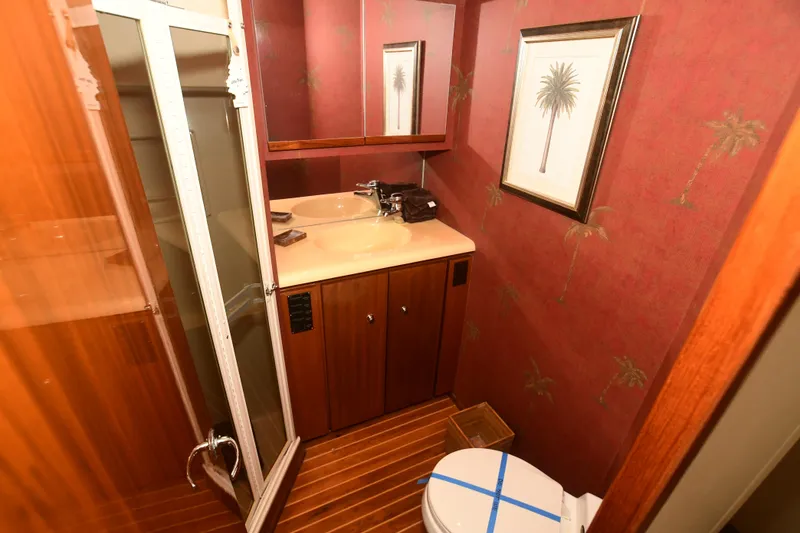 Slide: The Image of Bathroom interior of a 2000 Viking 65 Convertible yacht with wooden cabinetry and palm tree wallpaper. - 24