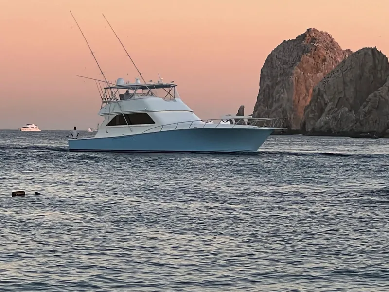 Slide: The Image of Viking 65 Convertible yacht cruising near rocky coastline at sunset, 2000 model. - 6