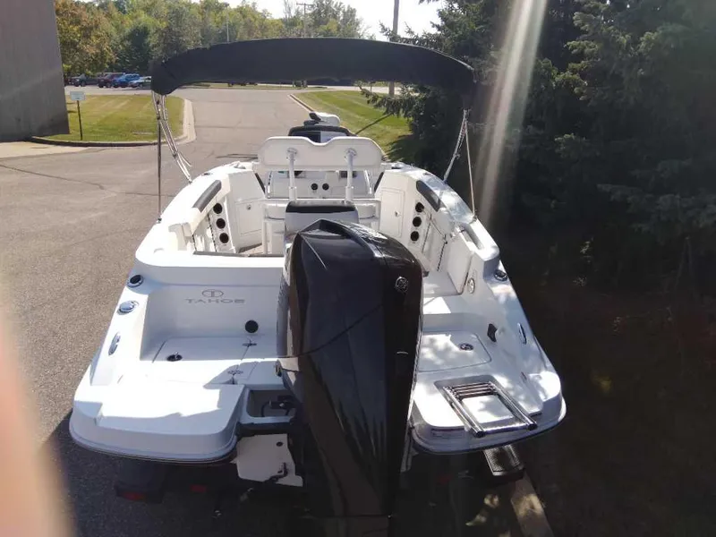 Slide: The Image of 2023 Tahoe 2150 CC boat with outboard motor, parked outdoors. - 1