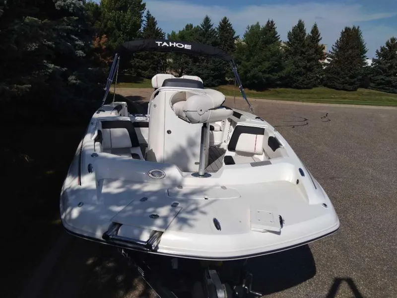 Slide: The Image of 2023 Tahoe 2150 CC boat on pavement, surrounded by trees. - 2